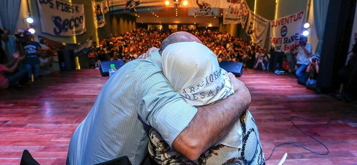 Hebe de Bonafini y el presidente del Frente Grande Mario Secco de espaldas abrazandose en un acto dentro de un teatro